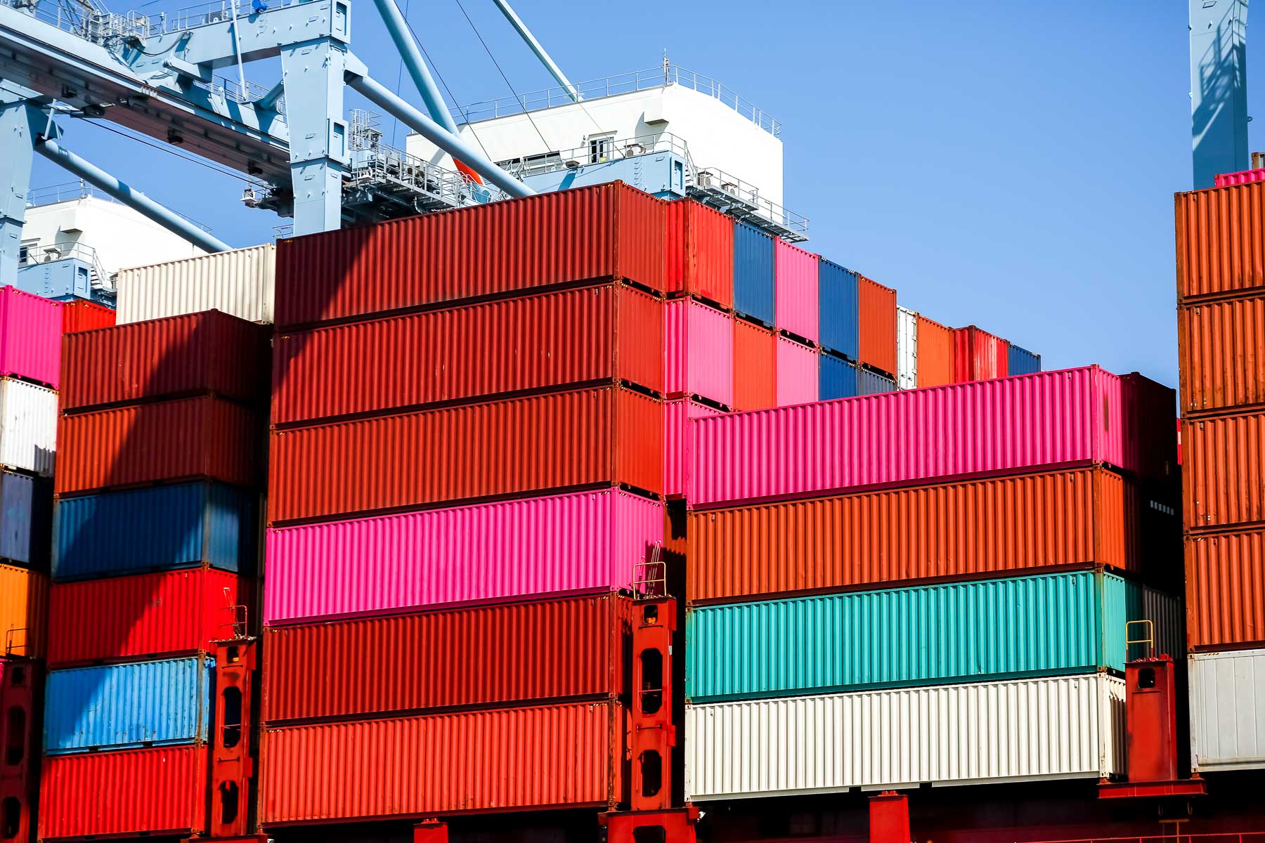 Stacks of colorful shipping containers under a clear blue sky.