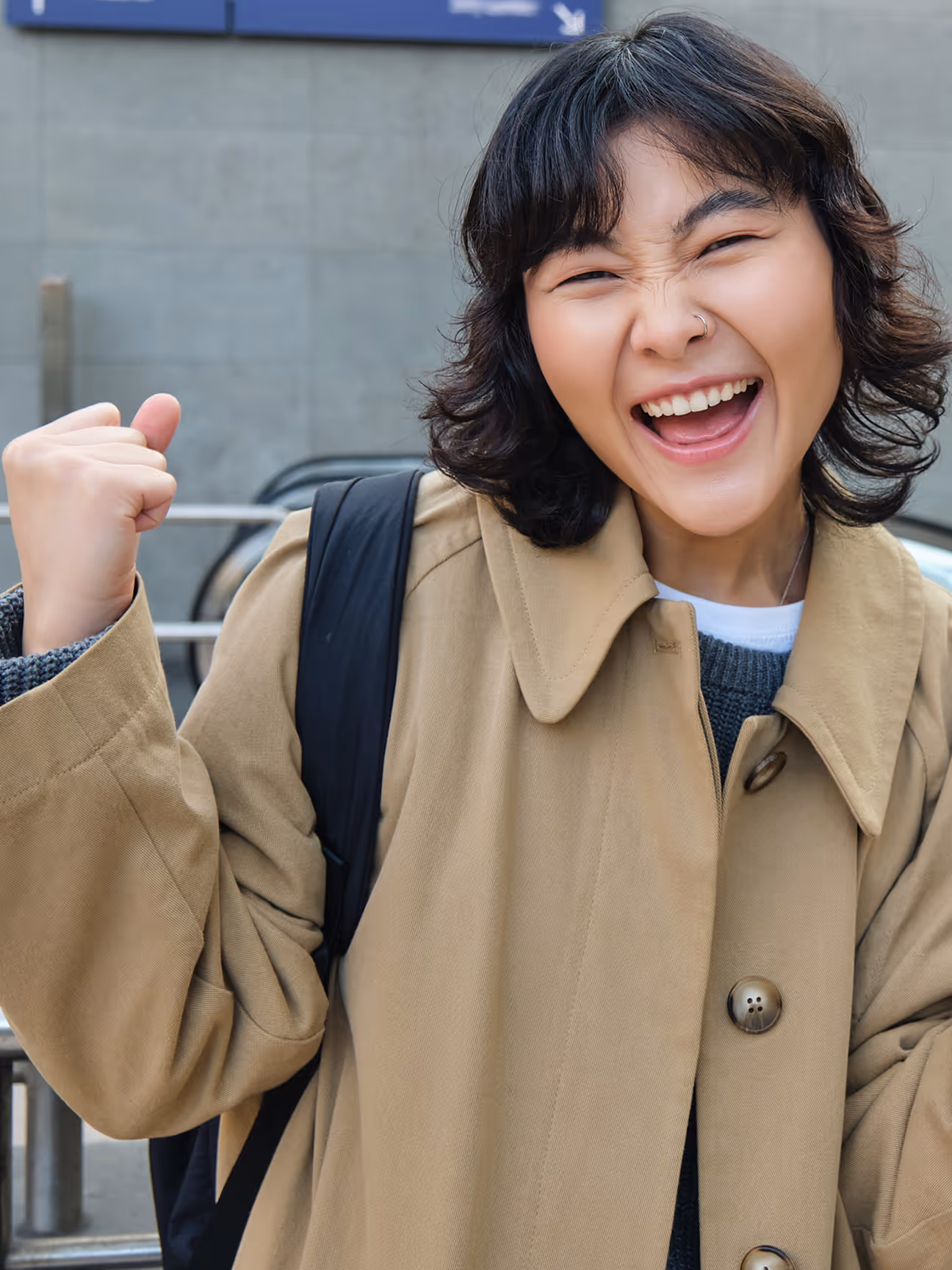An Asian girl smiling and making an hand gesture of excitement