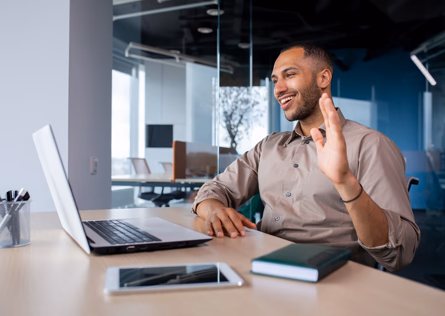 A man waving at a laptop, probably in a conference call