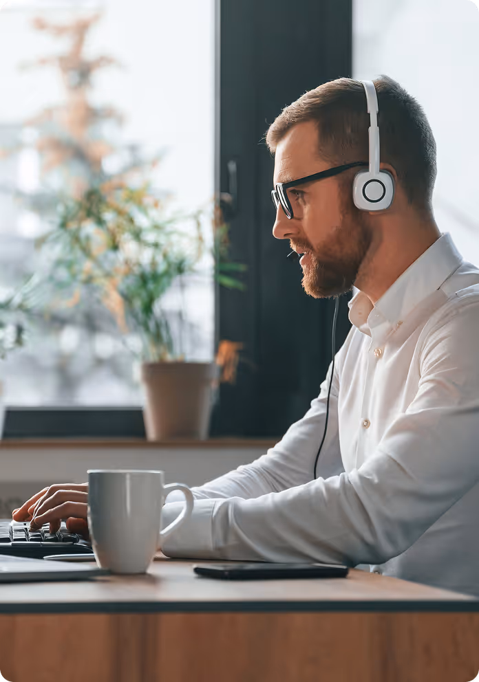 A developer with headphones working on a laptop in the modern office