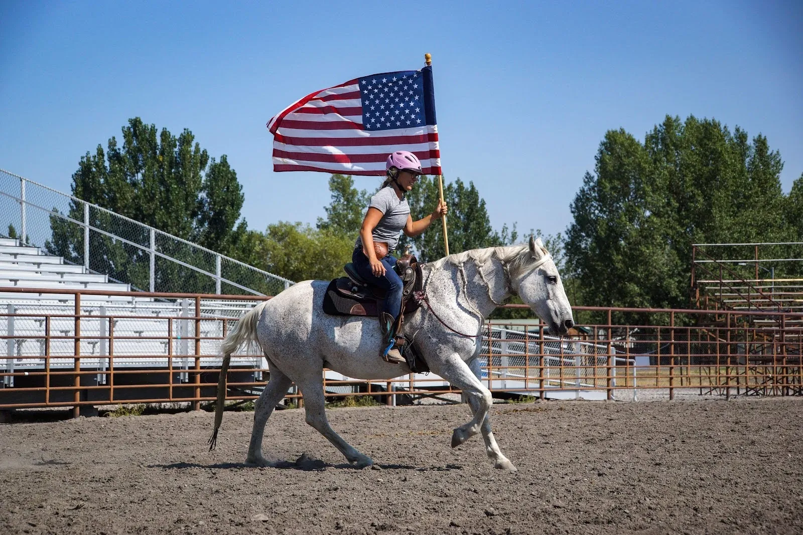 A woman riding a horse while holding the American flag.