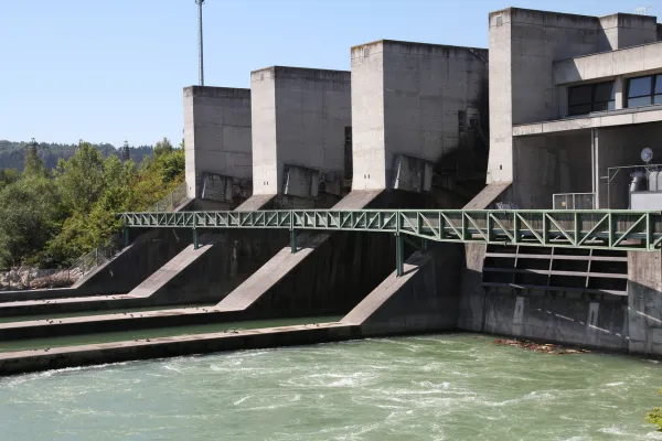 Aerial view of a hydropower dam and lock system with adjacent railway and urban infrastructure.