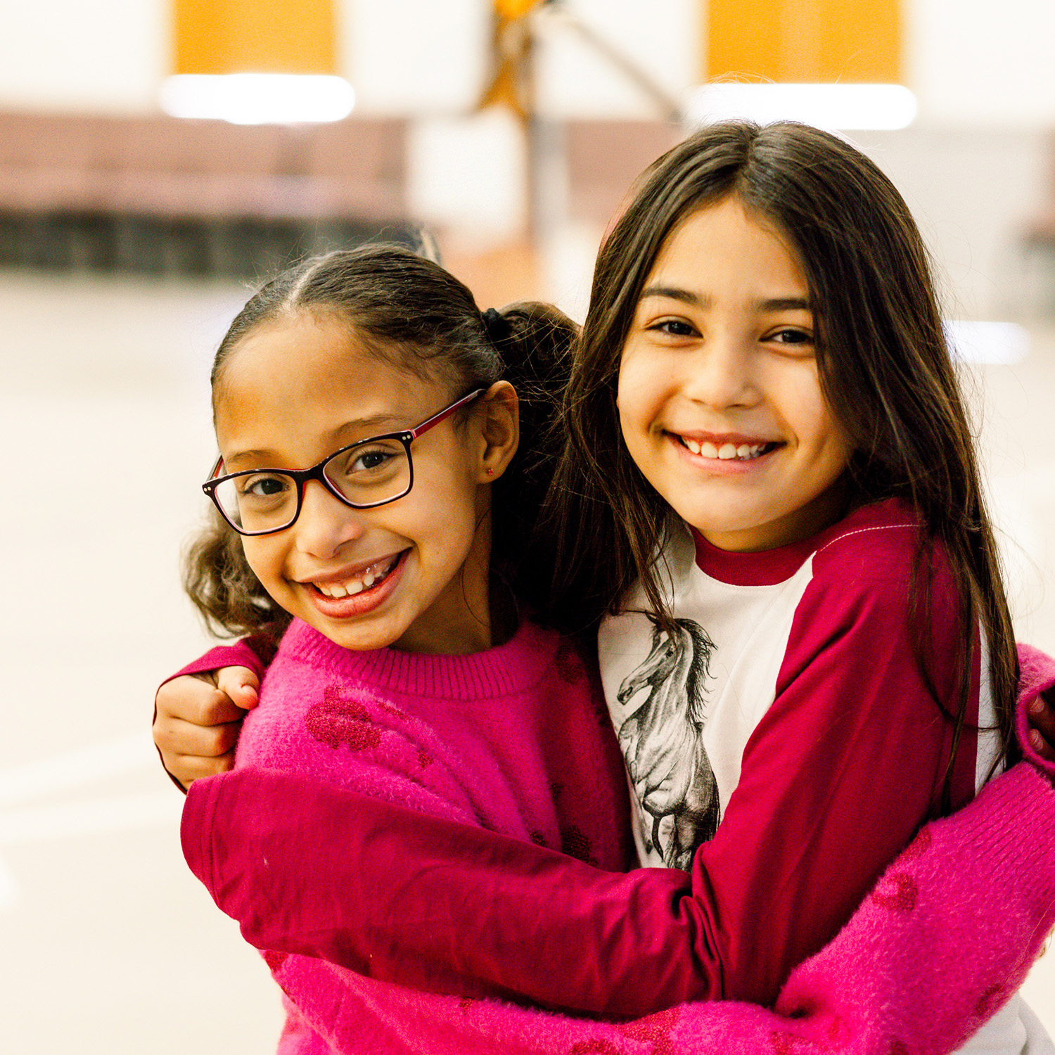 Two Elementary girls have their arms wrapped around each other and smile for a picture on Elementary fun day