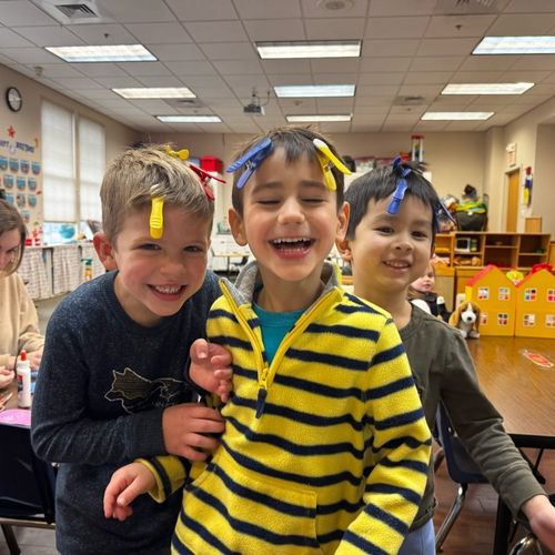 Three preschool boys smile and laugh as they have clothespins in their hair