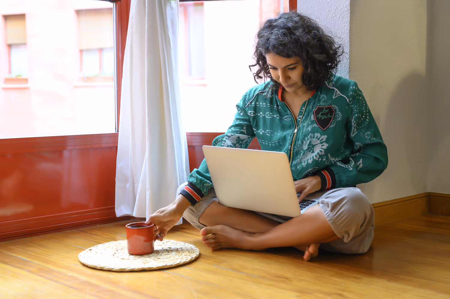 Woman holding a mug while using a laptop