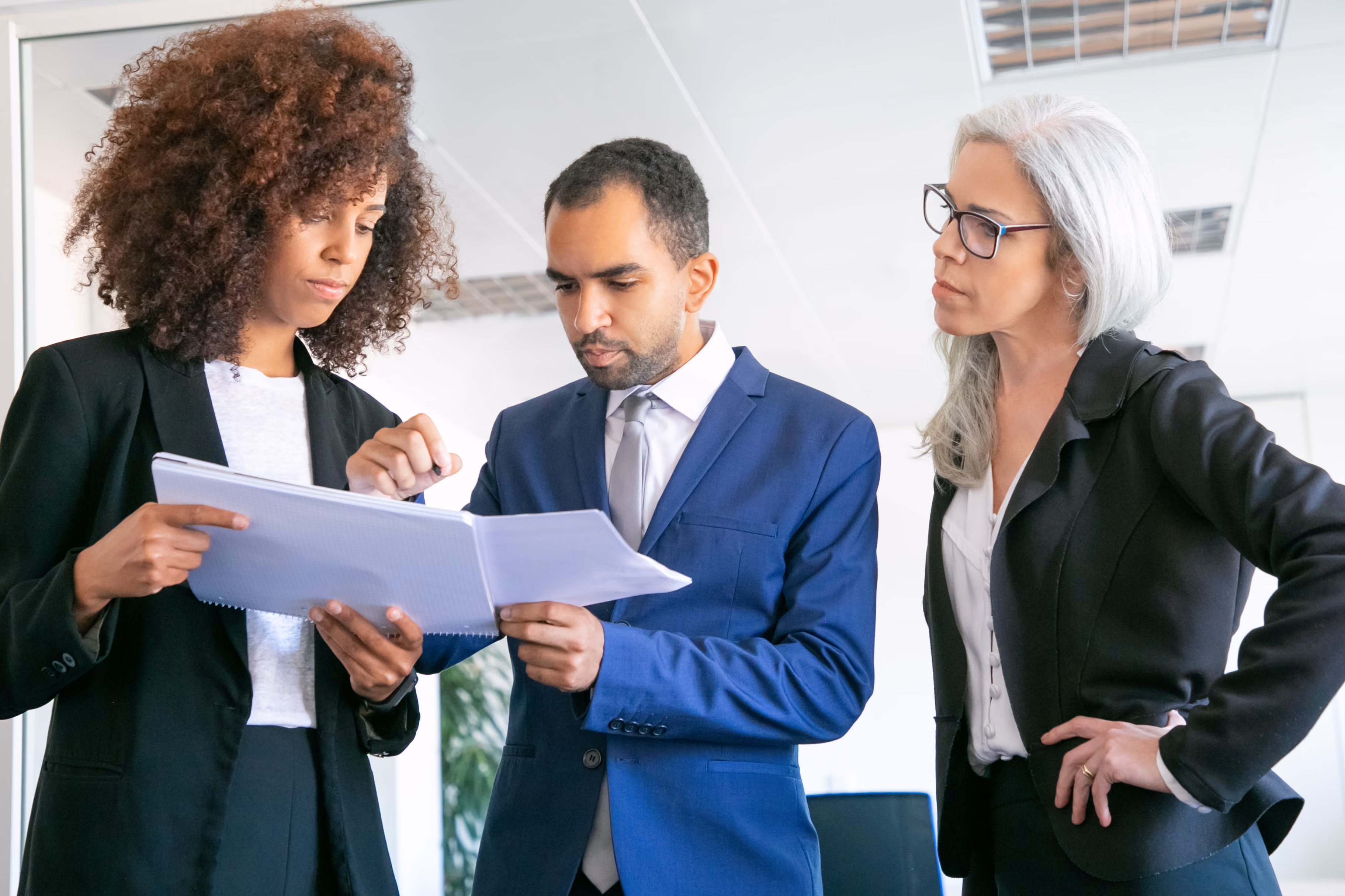 Three colleagues in business clothes reviewing papers together in an office