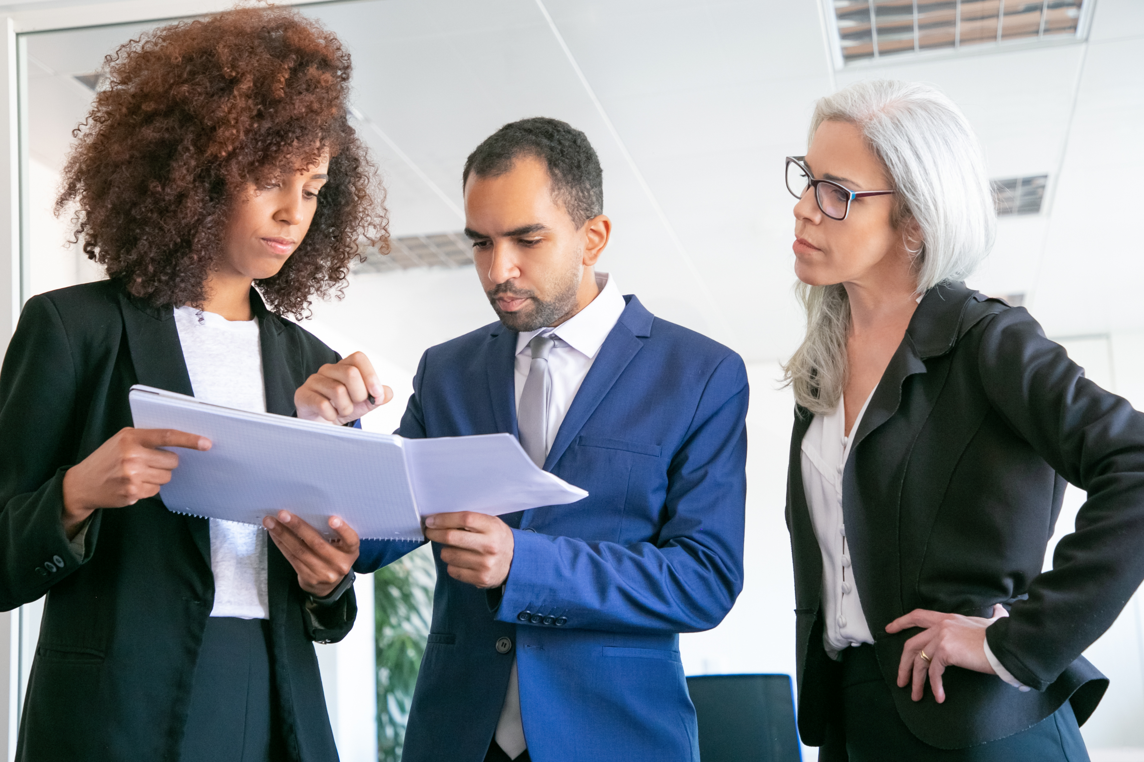 Three colleagues in business clothes reviewing papers together in an office