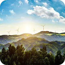 Wind turbines on a mountain ridge with a bright sky and scattered clouds at sunrise or sunset.