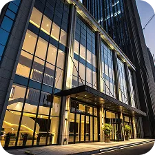 Modern building entrance with large glass windows and illuminated lobby at dusk.