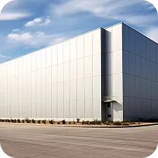 Exterior view of a large, modern industrial warehouse building under a partly cloudy sky.