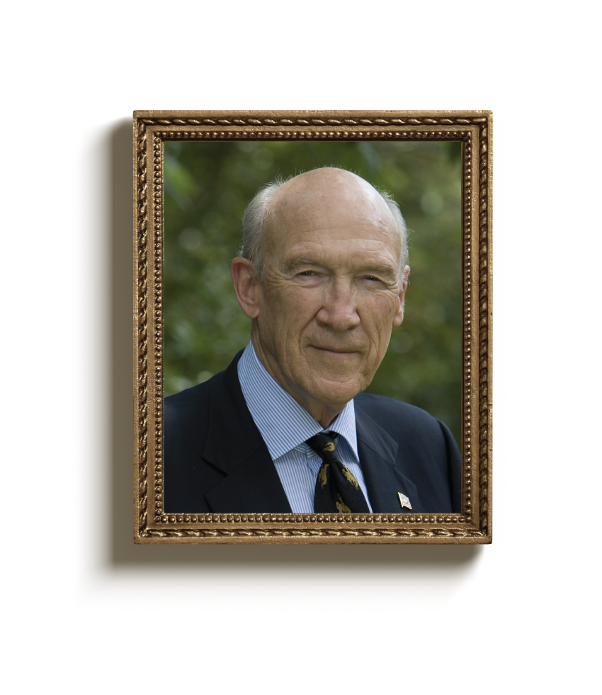 Portrait of an elderly man with a bald head wearing a suit, striped shirt, and patterned tie in a decorative gold frame.