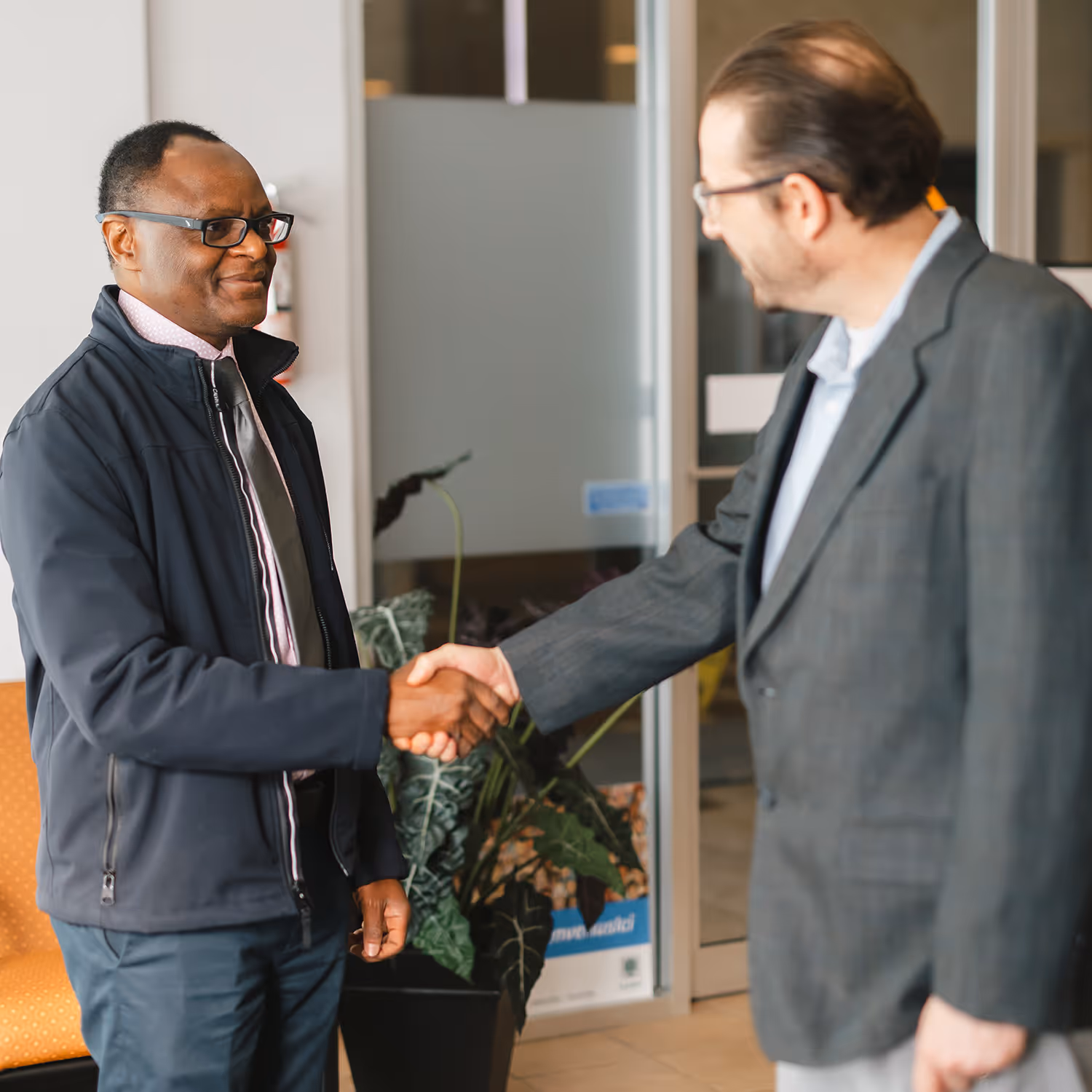 Job seeker and employer smiling and shaking hands in an office setting