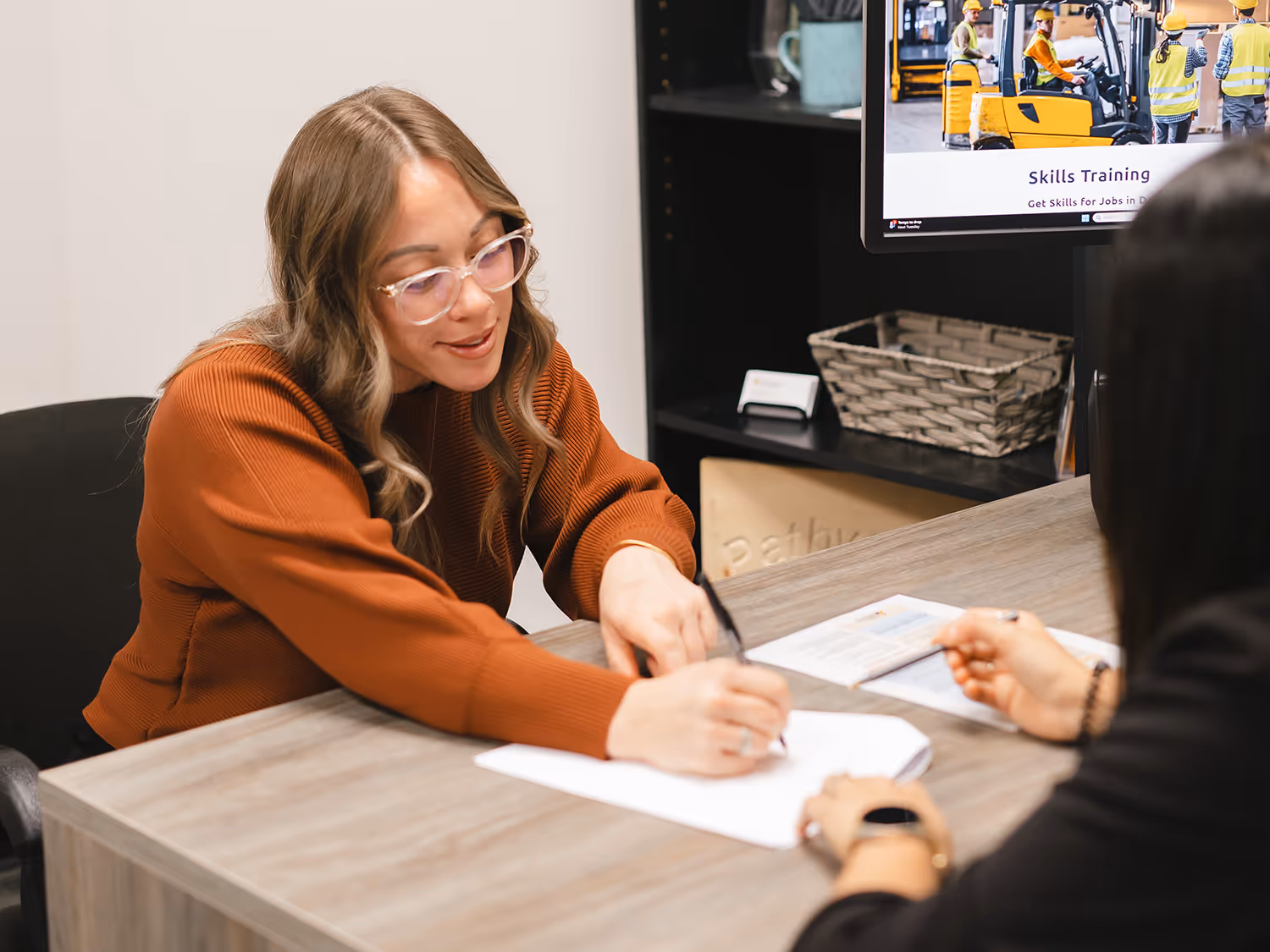 Pathways client sitting with staff member at desk, signing paperwork