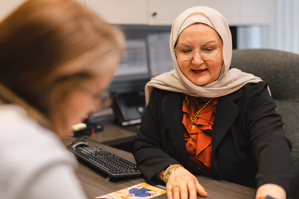 Pathways staff member at desk speaking with a client and looking at documents