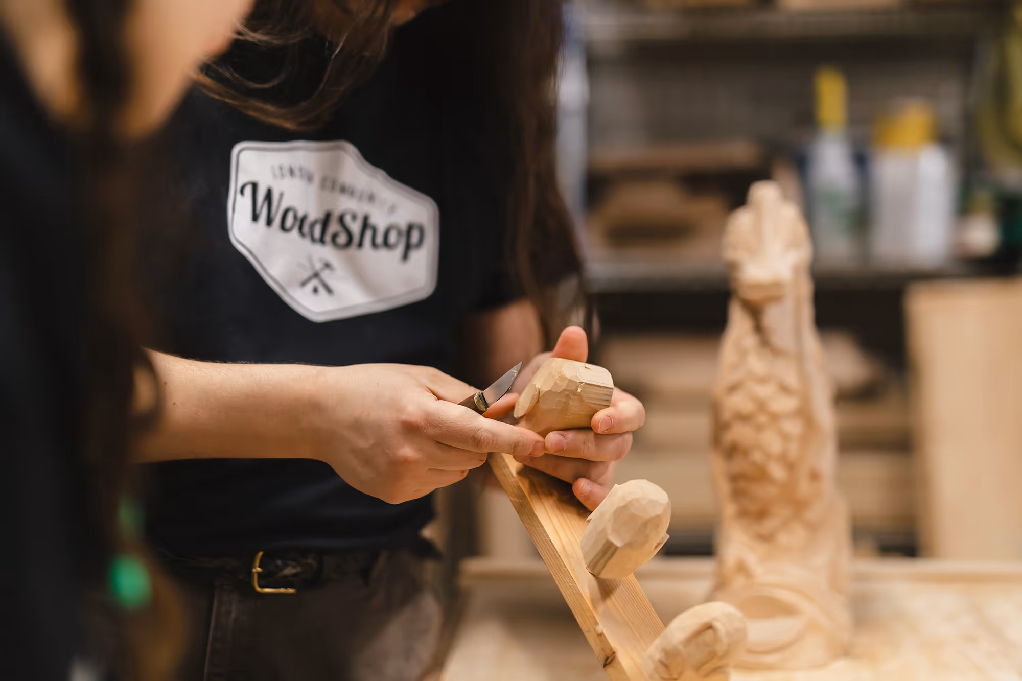 Close up of Woodshop instructor using carving tool to add detail to block of wood