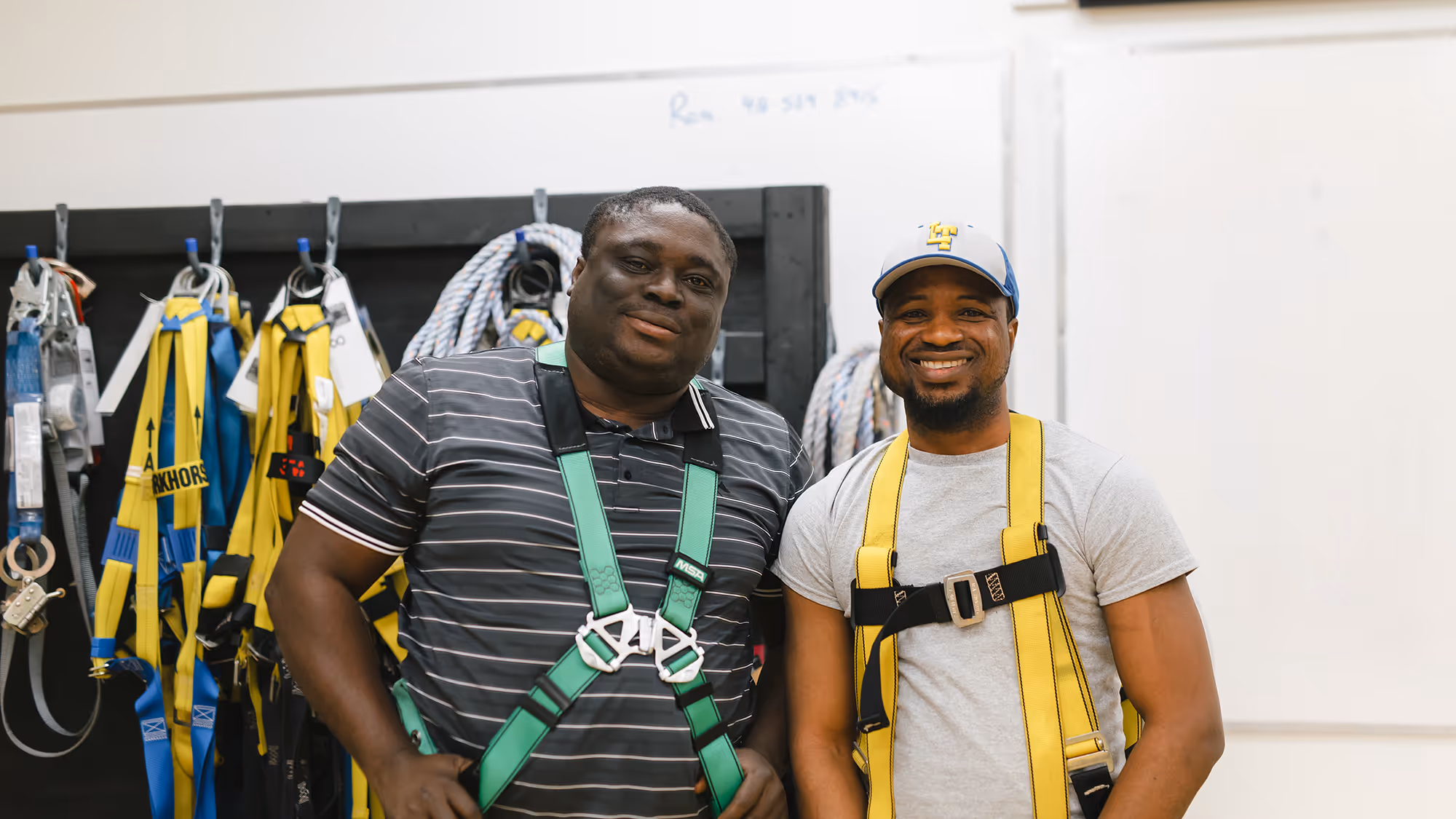 Two Pathways Certifications participants wearing safety harnesses and smiling for camera