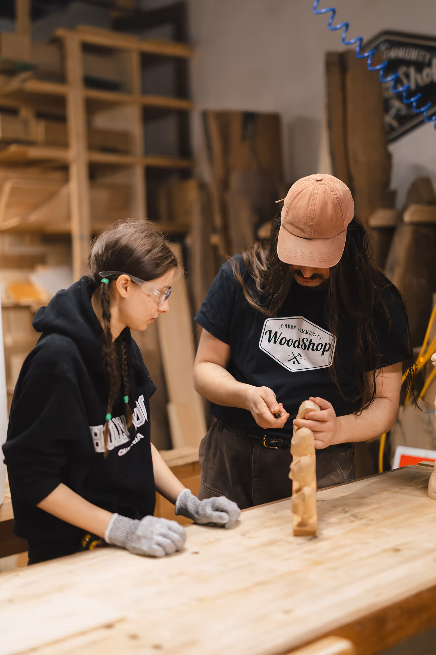 Pathways woodshop instructor demonstrates technique on block of wood while student looks on