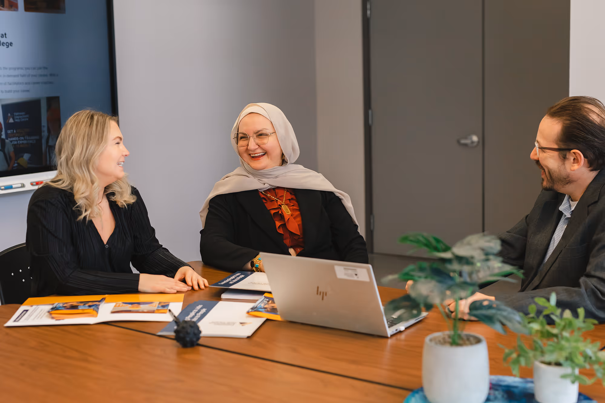 Three Pathways team members smiling and talking together around boardroom table