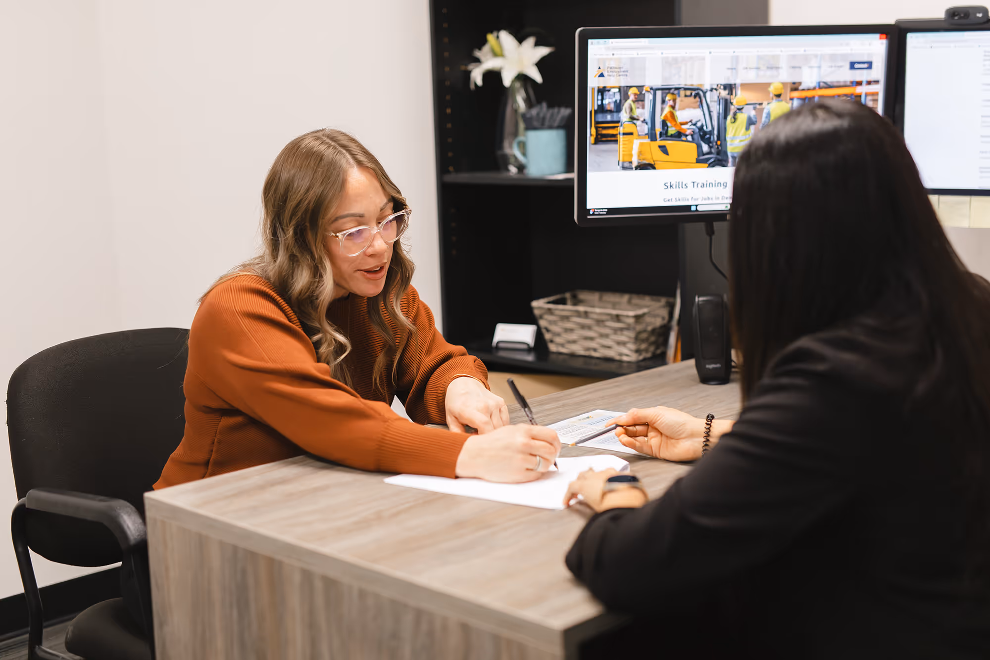 Pathways staff member and client sitting together at desk, filling out paperwork together
