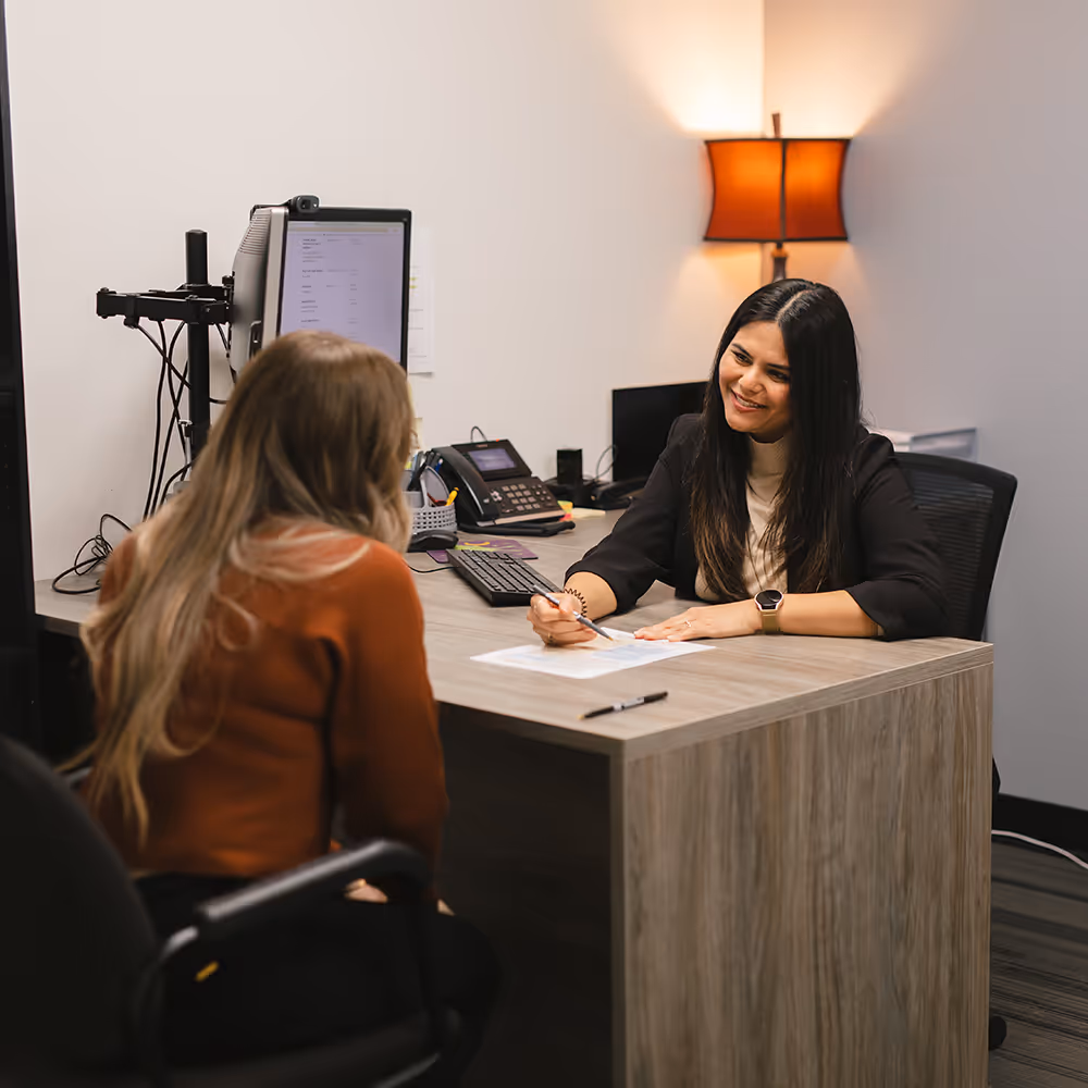 Smiling Pathways staff member sitting at desk with client, helping them with forms