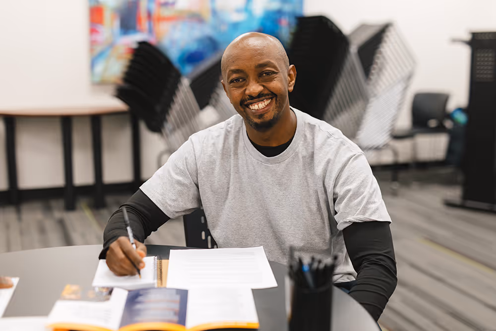 Smiling Pathways student sitting at table working on coursework