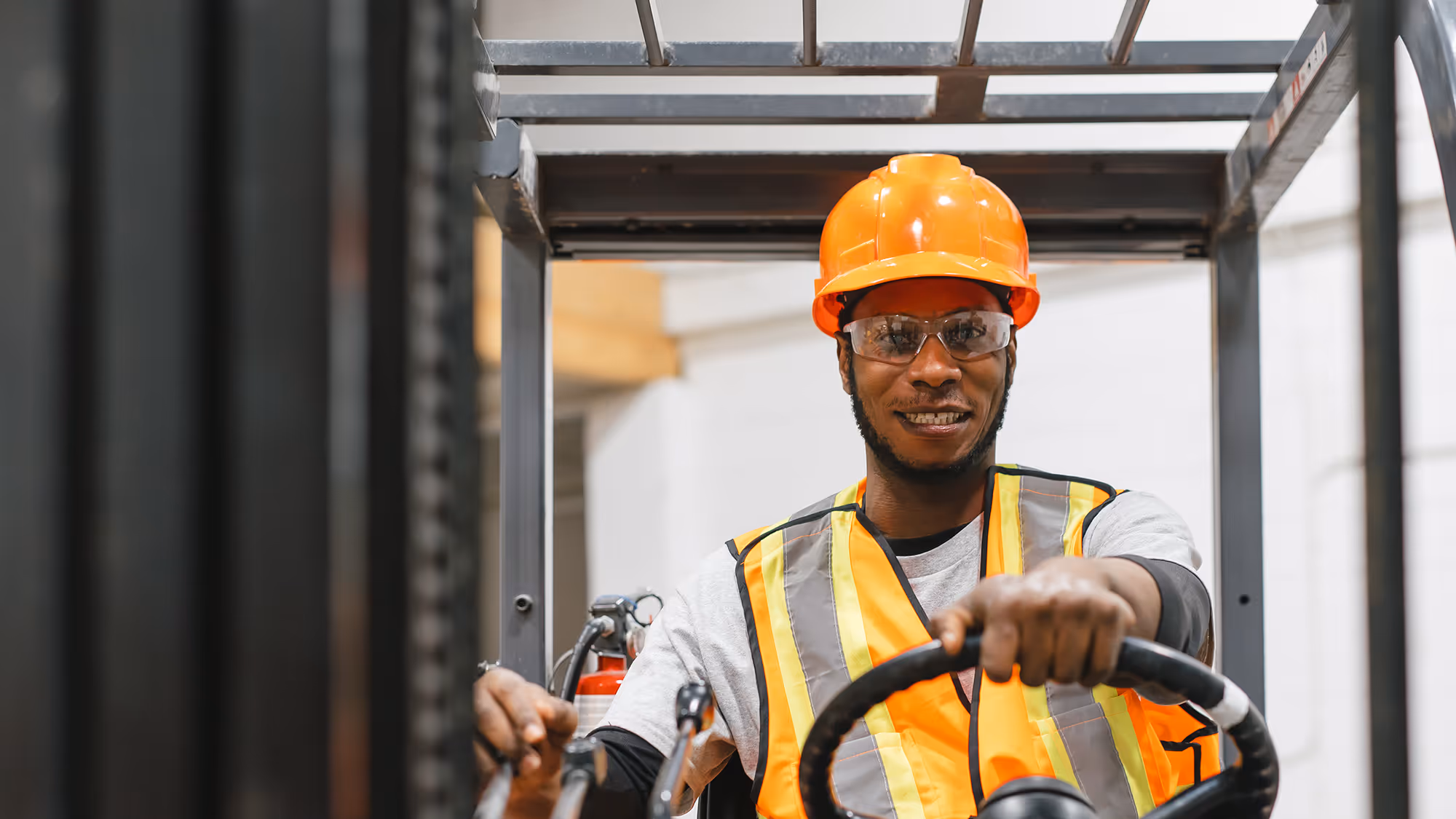 Pathways student in hi-vis vest and hard hat, operating a forklift 