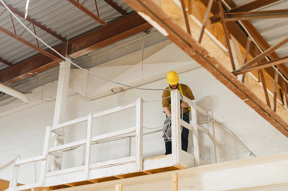 Pathways Working at Heights certification participant standing on a high wooden platform in warehouse space