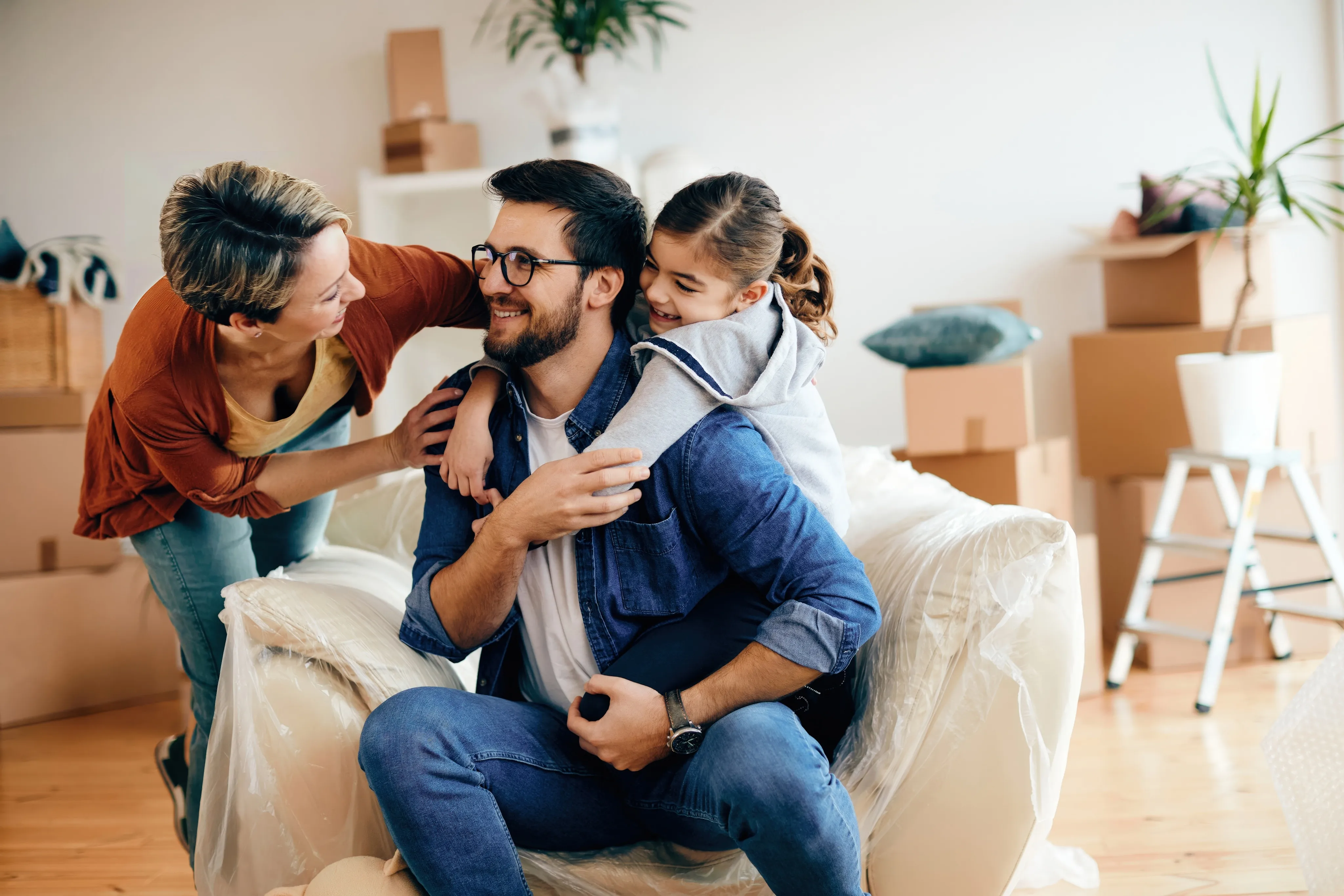 Happy family with young daughter unpacking boxes in new home, protected by independent insurance agency in South Florida.
