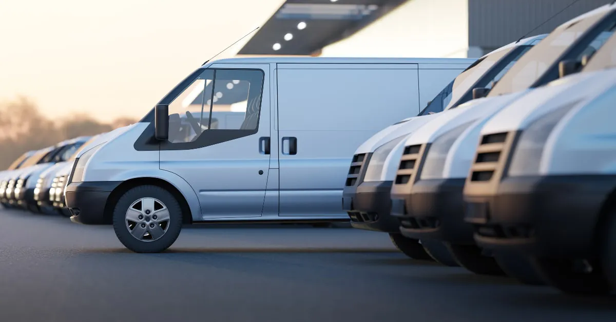 A fleet of white commercial vans parked at a business location, representing commercial vehicle insurance provided by an independent insurance agency in South Florida.