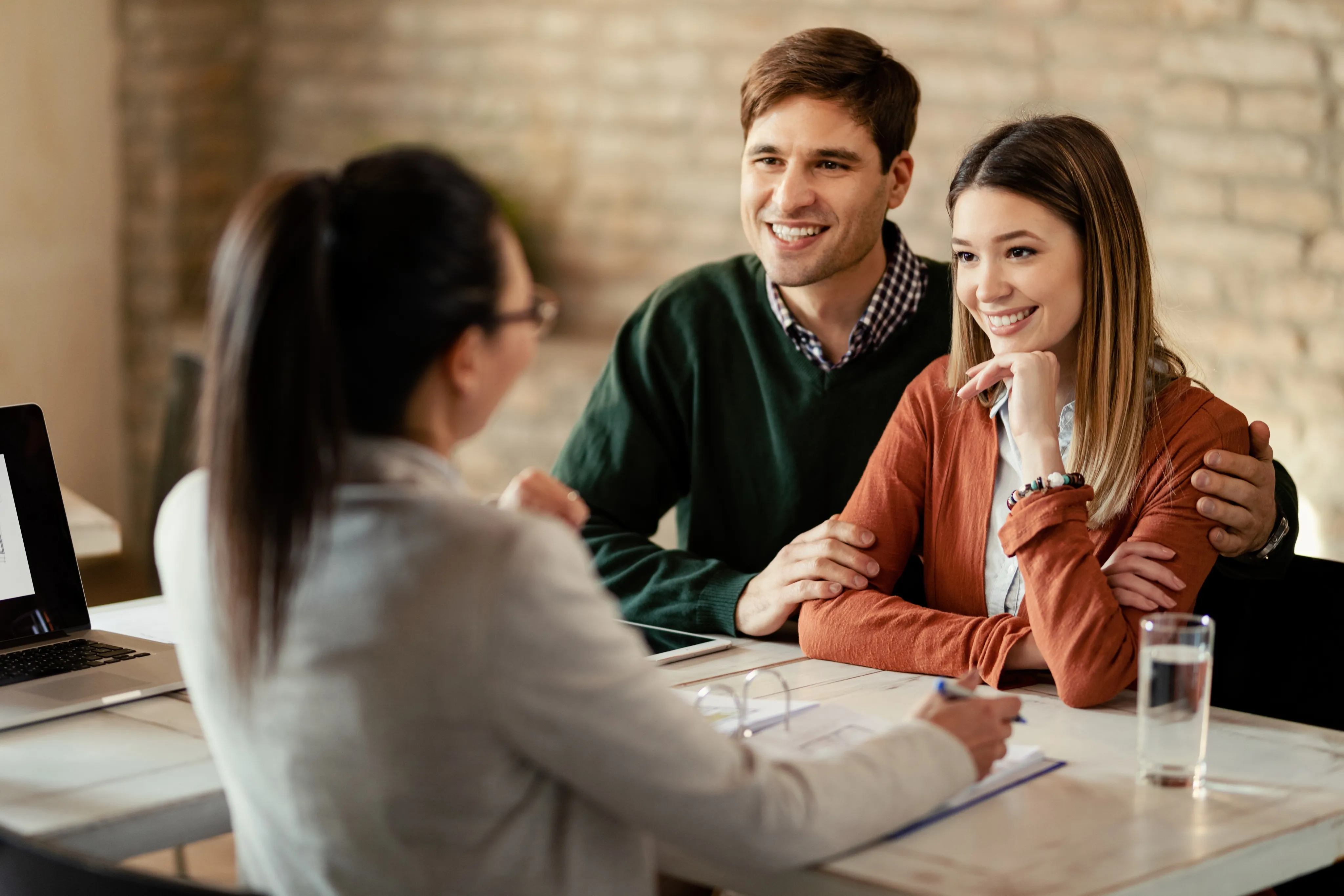  A cheerful couple meets with an advisor at a desk to discuss their needs, reflecting the personalized guidance offered by an independent insurance agency in South Florida.