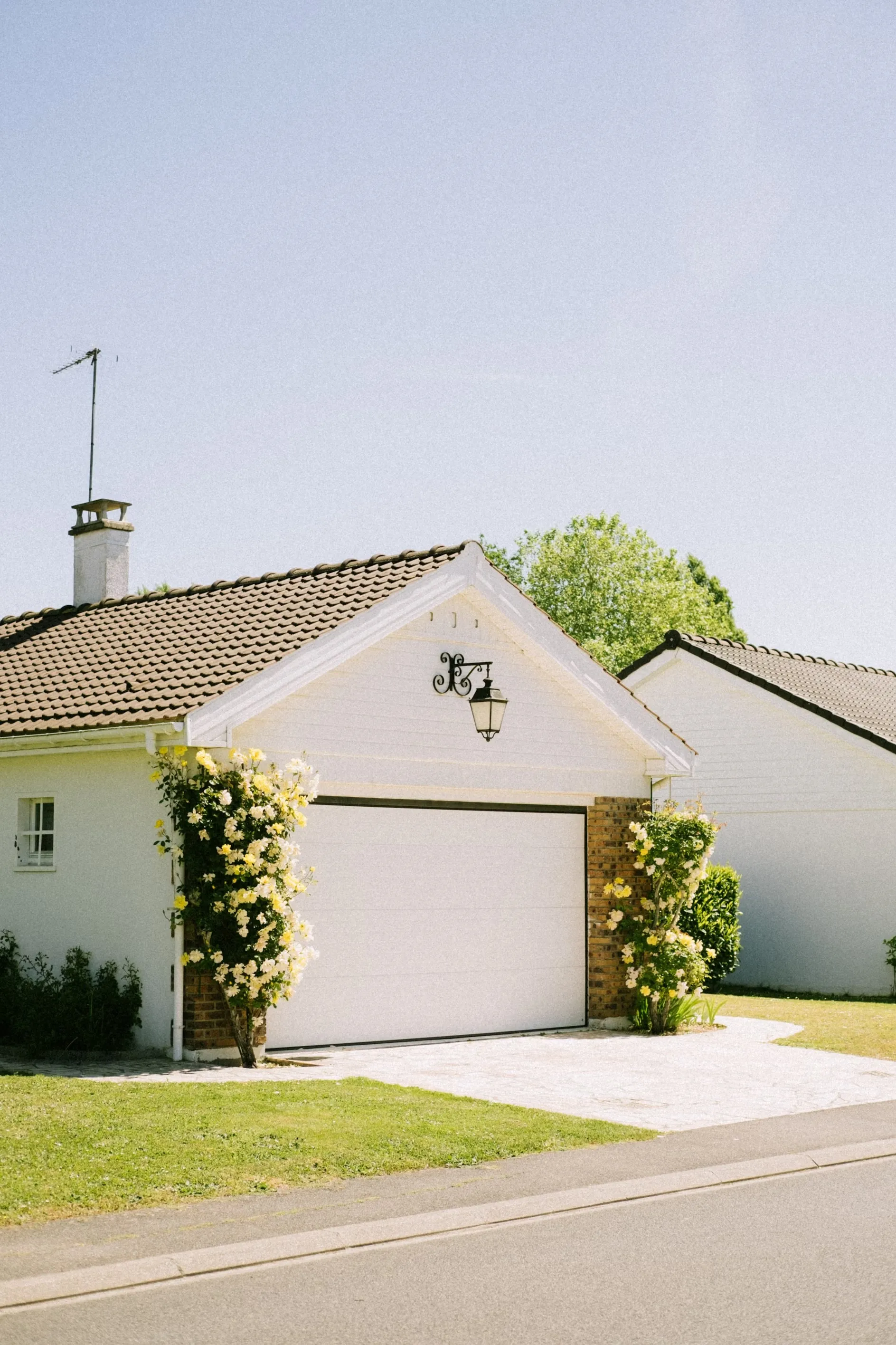 A charming white house with blooming yellow flowers and a tidy front yard, representing the pride of homeownership and the comprehensive protection available from an independent insurance agency in South Florida.