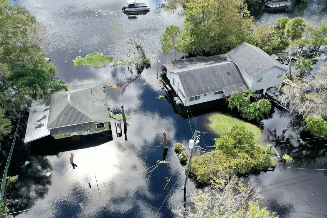 Aerial view of two homes surrounded by floodwaters and submerged yards, showing why homeowners trust an independent insurance agency in South Florida for comprehensive flood insurance solutions.