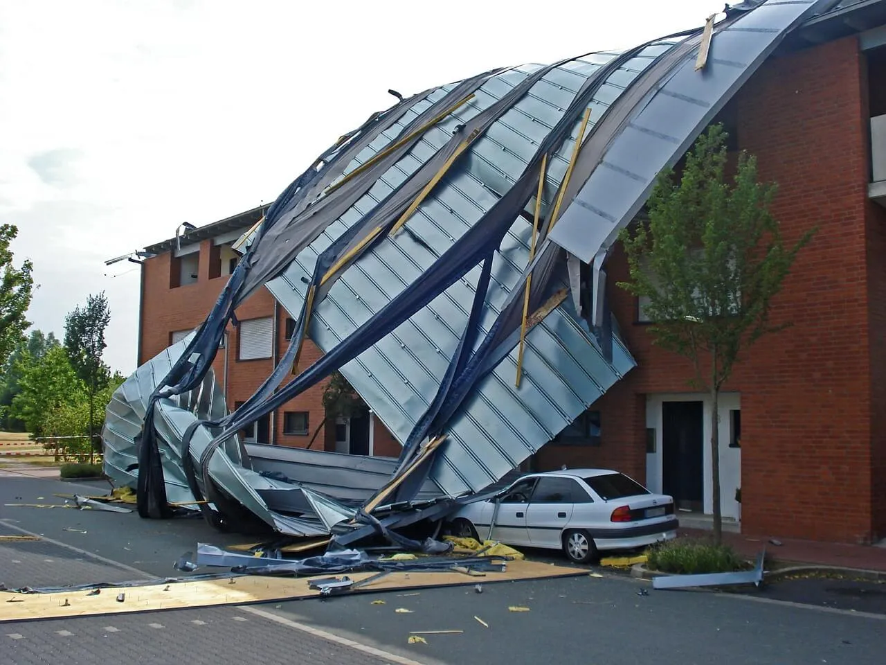 A collapsed metal roof covers a car and brick building at South Florida businesses.