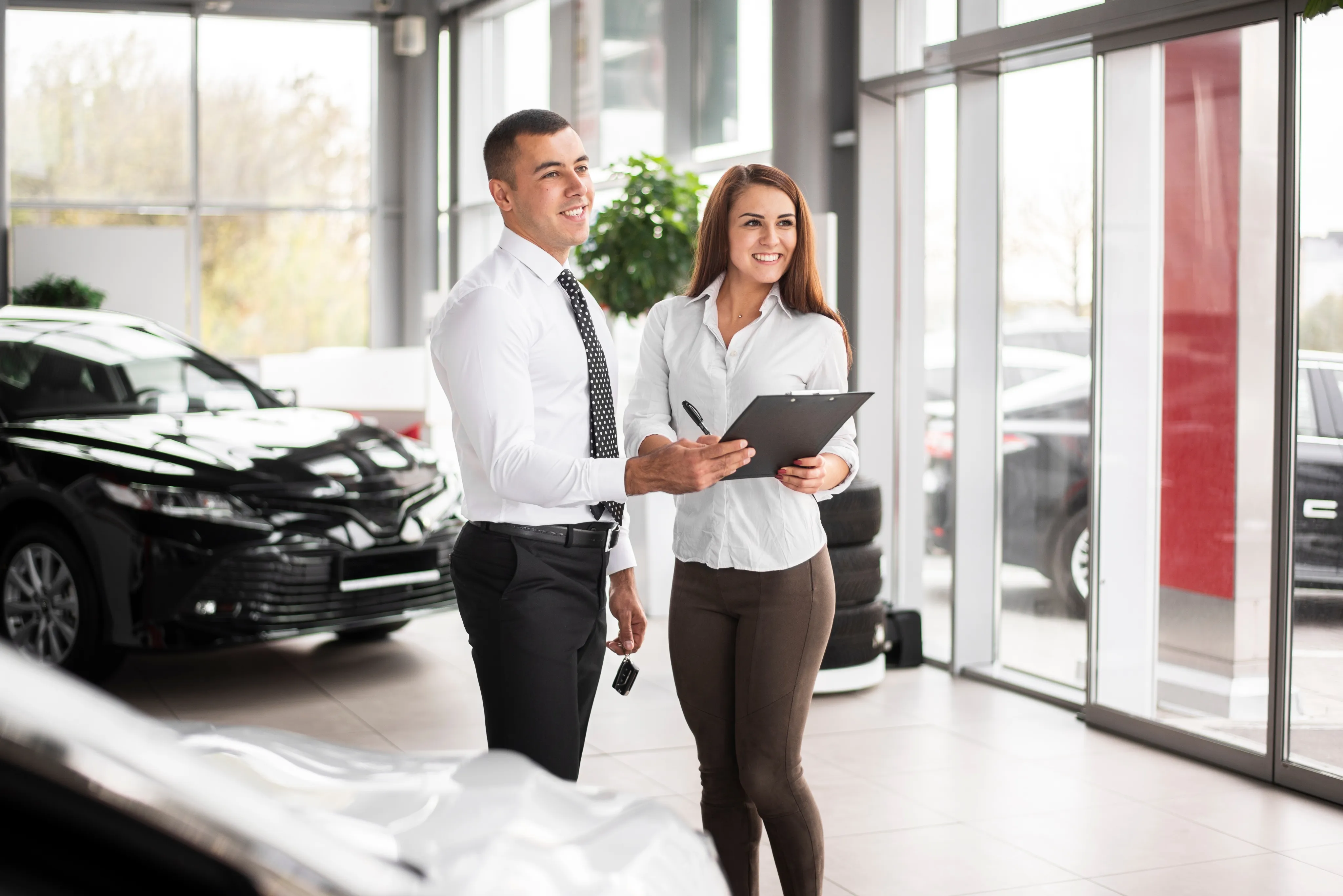 Two people in business attire smiling and talking about commercial auto insurance.