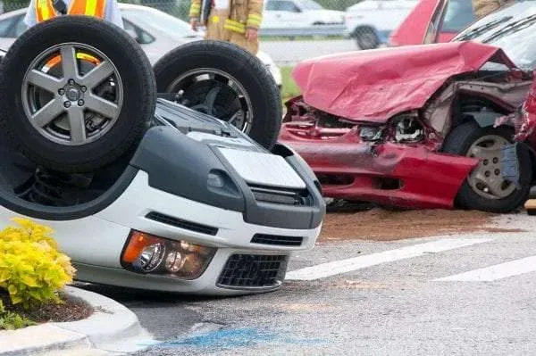 Overturned white car beside a red car in South Florida after a commercial auto accident.