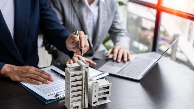 Two people review documents and a laptop, discussing business property insurance.