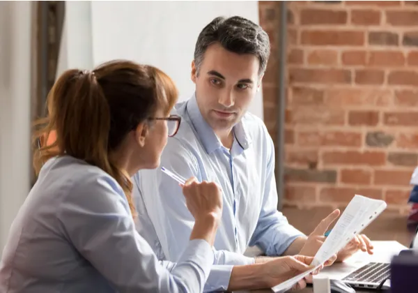 Two colleagues discussing commercial property insurance documents at an office desk.