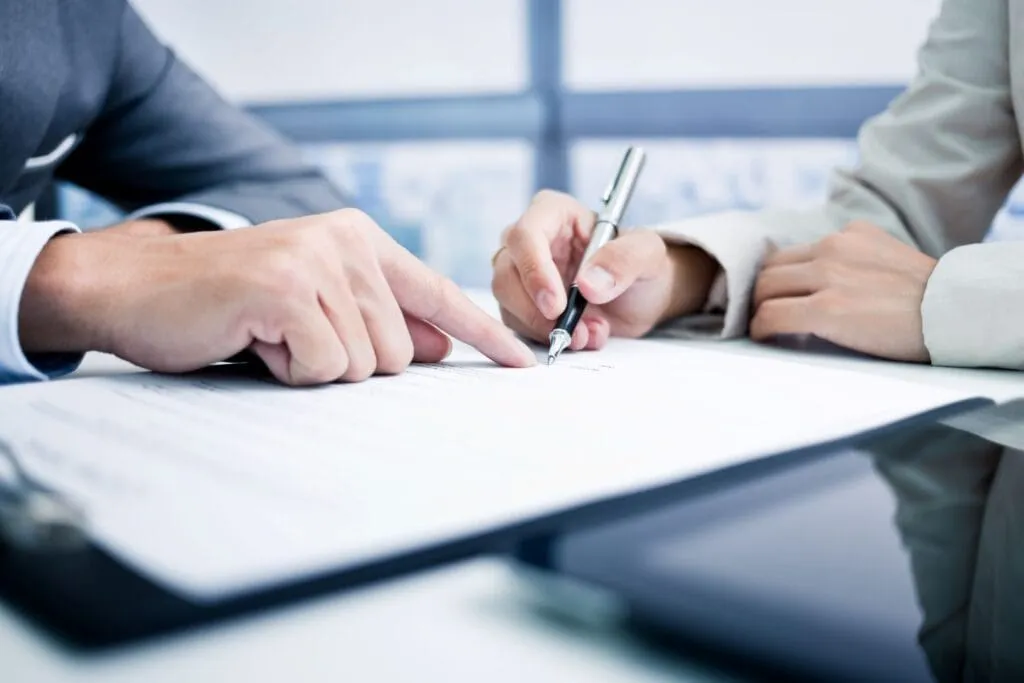 Two people sign a document at a desk, discussing Florida business legal claims.