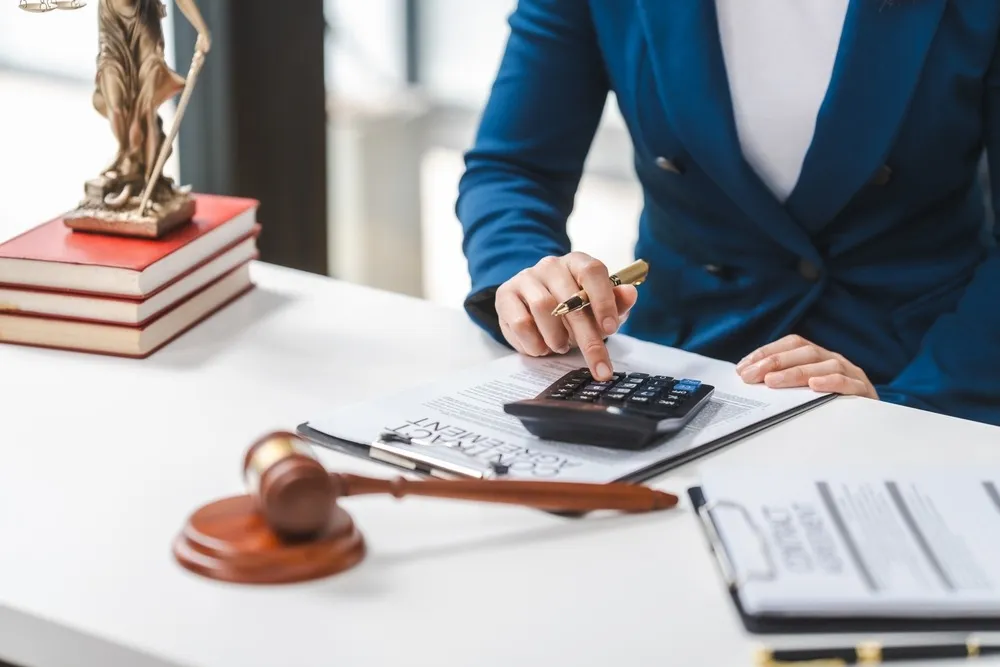 Person in blue blazer uses calculator at desk with legal claims for a Florida business.