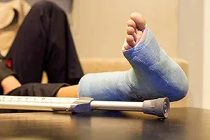 Person with leg in a blue cast resting, perhaps considering legal claims or coverage.