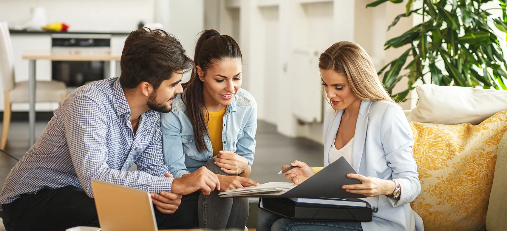 Three people sit together, reviewing documents in a bright, modern office setting.