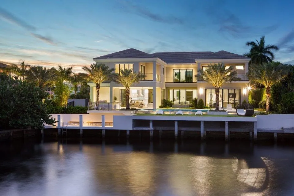 Modern Boca Raton waterfront mansion illuminated at sunset, showcasing luxury living for Florida homeowners insurance.