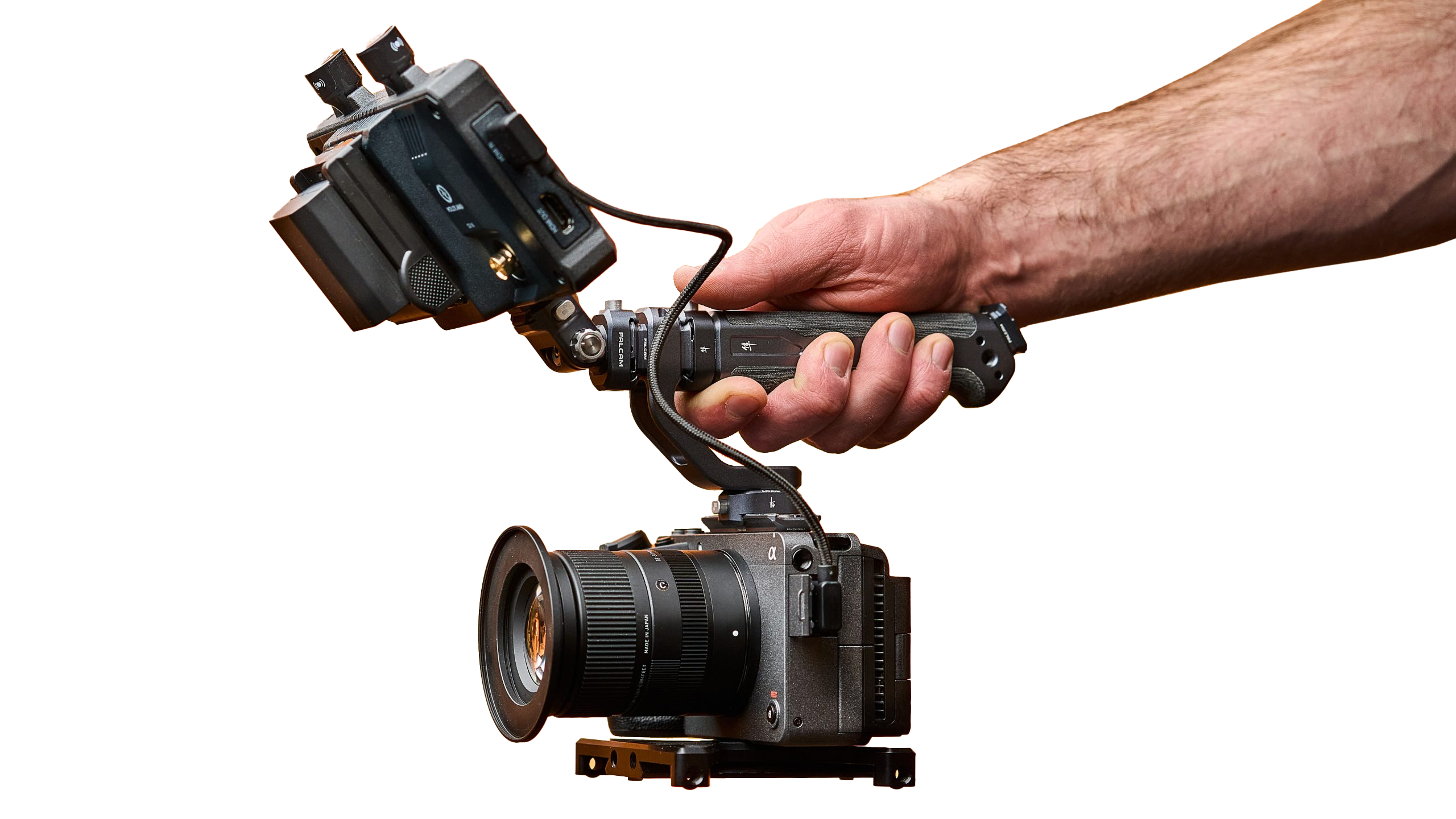 Close-up of a person’s hand holding a professional camera rig with a large lens and a mounted external monitor.