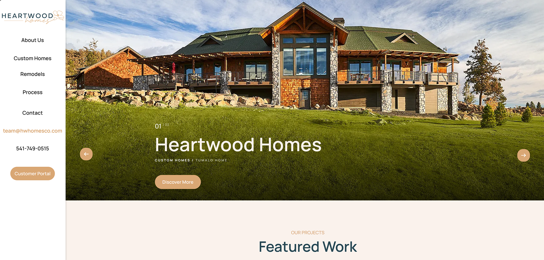 Large modern custom home with stone and wood exterior on a green lawn under a partly cloudy sky.