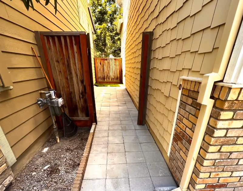 newly installed side yard concrete tile pathway in between two houses leading to backyard.