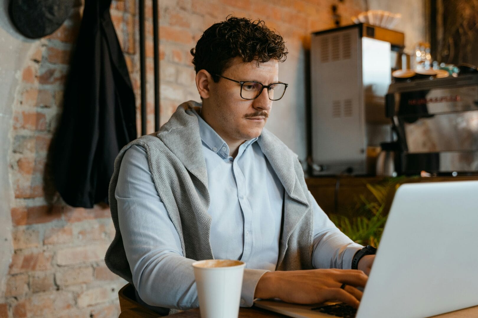 Person working on a laptop with a coffee cup on the desk.