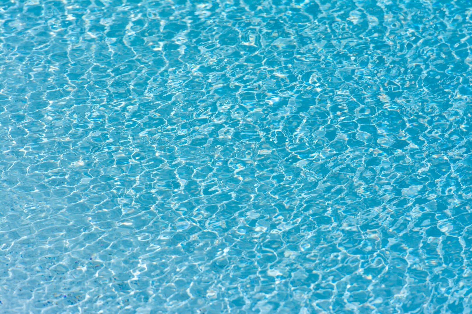Close-up of the surface of a swimming pool with clear blue water.
