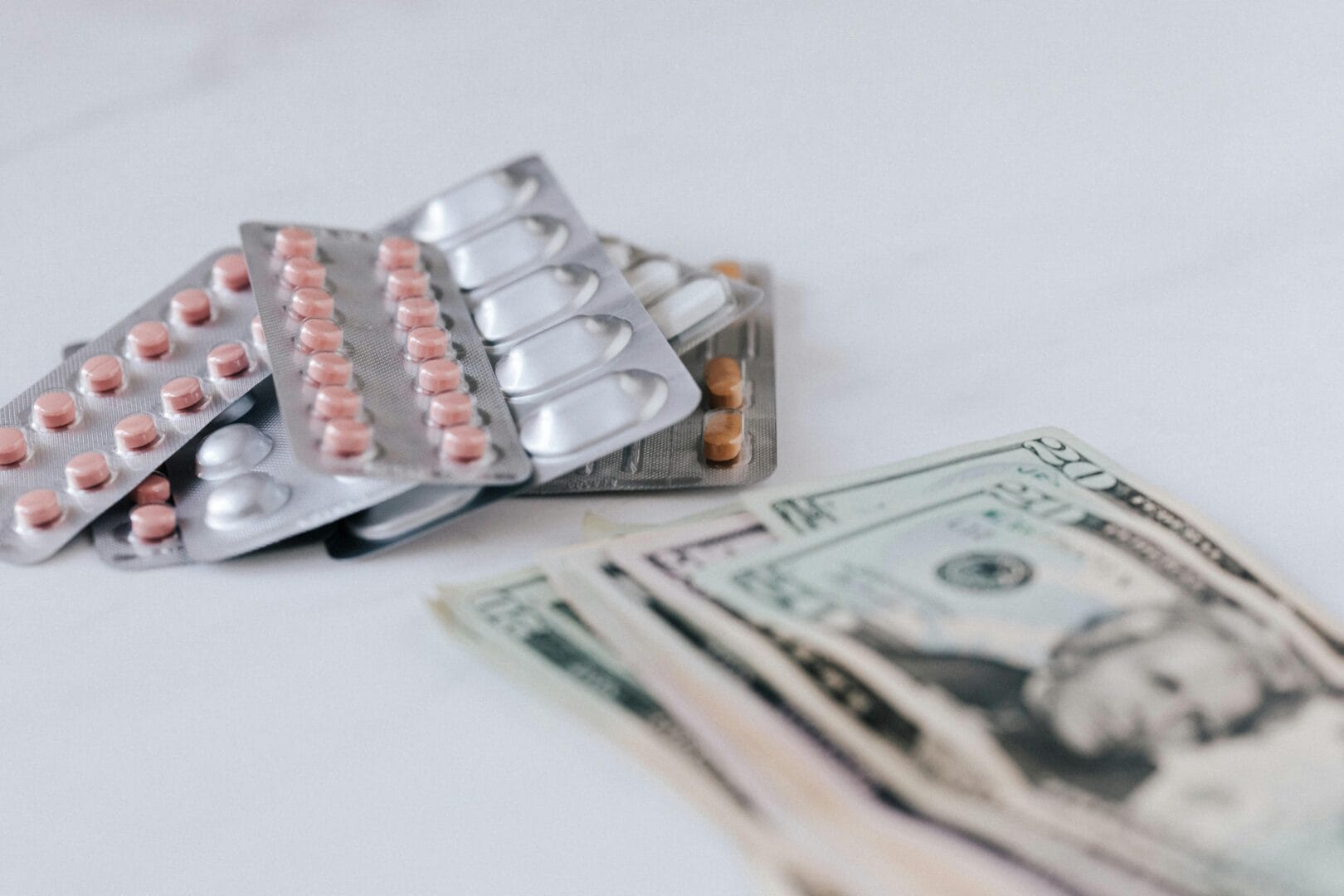Blister packs of pills next to a stack of US dollar bills.