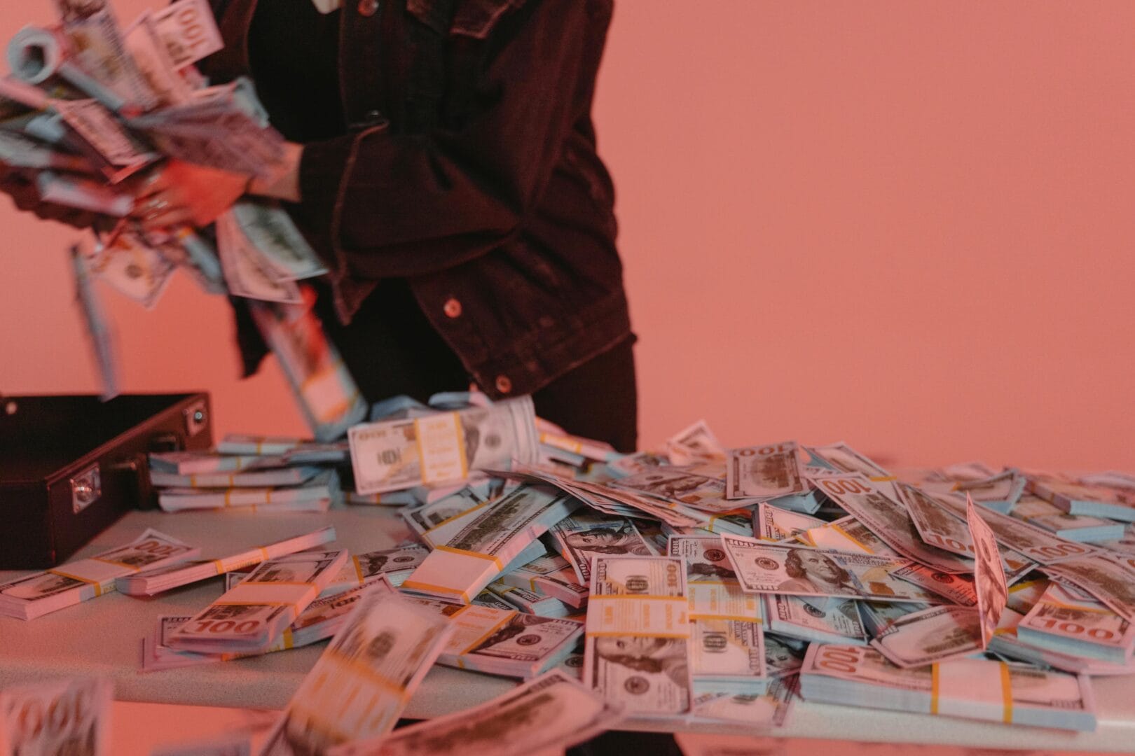Person handling a large amount of cash spread out on a table.
