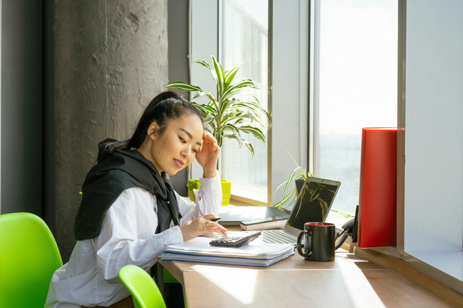 Woman sitting at a desk with a laptop and a calculator, working or studying.